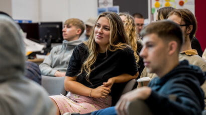 A girl sat in the middle of a crowd of people at a lecture