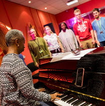 Students during a vocal lesson at the Centre for Music, accompanied by instructor playing piano