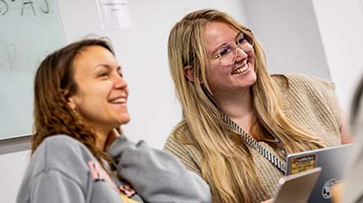 A couple of students leaning in together smiling