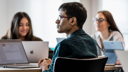Group of people at a table listening to a presentation.
