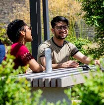 A couple of students smiling whilst chatting in the Frenchay campus walled garden.