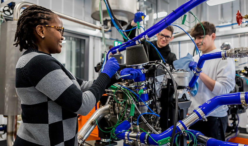 Three young people stood working with technical engineering equipment in a studio