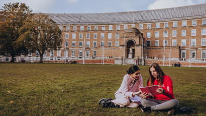 Two UWE Bristol students seated on the grass at College Green.